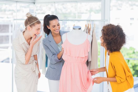 Attractive fashion designers looking at a dress on a mannequin