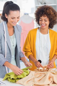 Cheerful fashion designers touching textile in a creative office