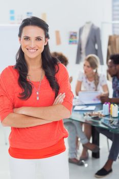 Pretty fashion designer with arms crossed in bright office smiling at camera