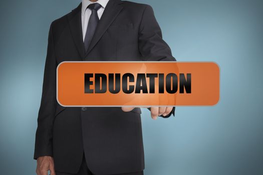 Businessman touching the word education written on tag on blue background
