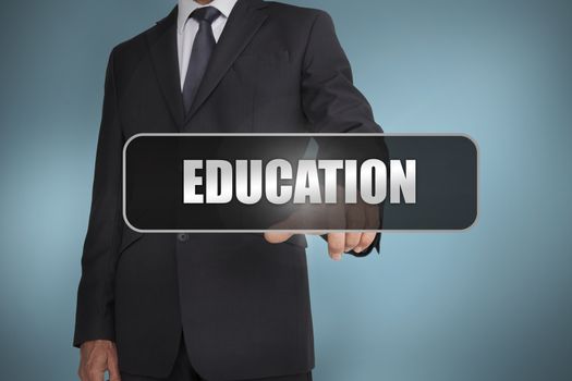 Businessman touching the word education written on black tag on blue background
