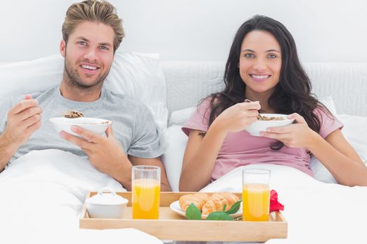 Couple eating cereal during a romantic breakfast in bed