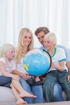 Happy family looking at globe on couch in living room