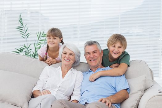 Grandchildren and grandparents sitting on couch in living room
