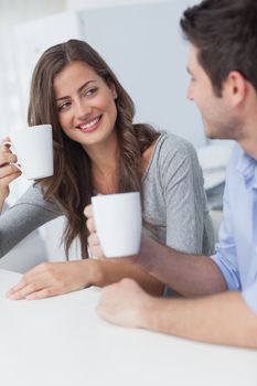 Cheerful couple drinking a cup of coffee in the kitchen