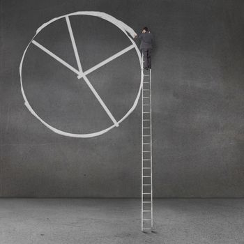 Businessman drawing a giant pie chart on a grey wall