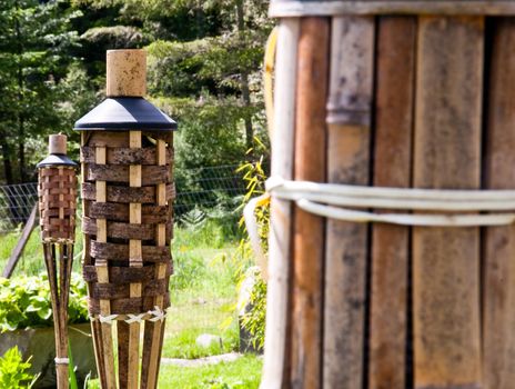 Tops of unlit tiki torches in a yard