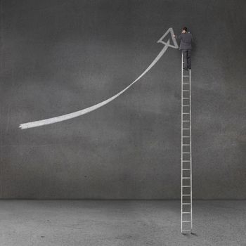 Businessman drawing a giant arrow on the grey wall of an empty room