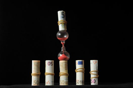 Business Time Concept Money and Hourglass on a Black Background