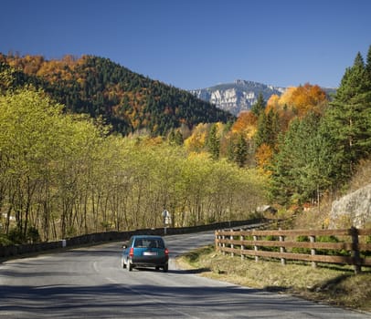 Moving car on road in autumn mountain landscape