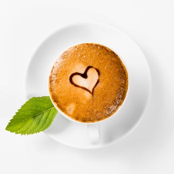 large cup of coffee with heart pattern on the foam and green leaf of mint