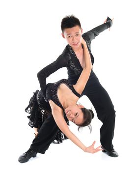 Modern young Asian teens couple latin dancers dancing in front of the studio background, full length isolated white.