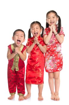 Group of oriental children wishing you a happy Chinese New Year, with traditional Cheongsam full length standing isolated on white background.