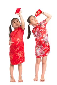 Happy Asian girls peeking into red packet during Chinese New Year, with traditional Cheongsam full length standing isolated on white background.