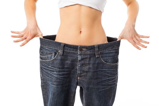 Woman showing her waist by wearing an old jeans, isolated on white