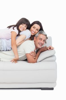 Little girl lying on her parents on sofa on white background