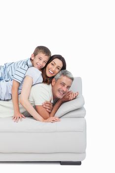 Little boy lying on his parents on sofa on white background