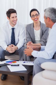 Cheerful business people talking and working together on sofa at office