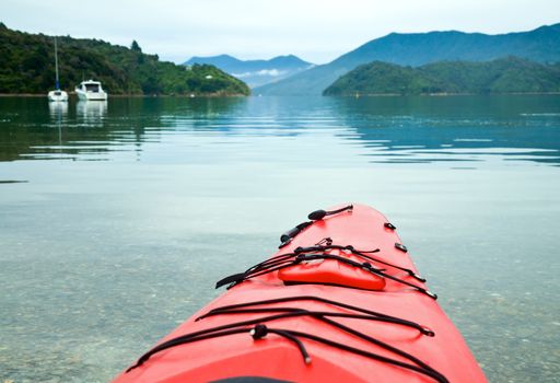 Red touring kayak in waters of the Marlborough Sounds, New Zealand