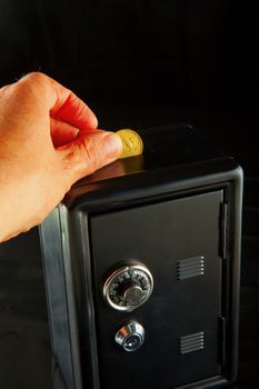 Male hand putting money in a black stronbox