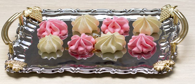 Yellow and pink meringues on a tray