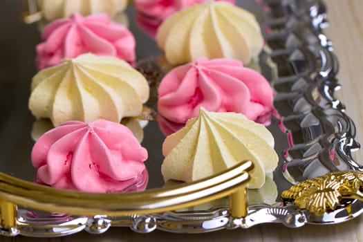 Yellow and pink meringues on a tray