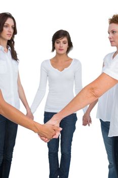 Pensive women standing and holding hands in a circle on white background
