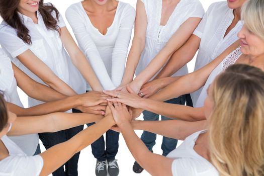 Female models joining hands in a circle on white background