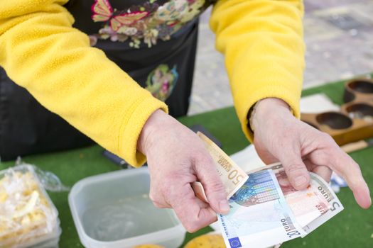 Woman seller returns change in euro in the market