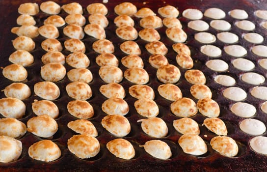 freshly baked traditional Dutch mini pancakes called "poffertjes" on the oven