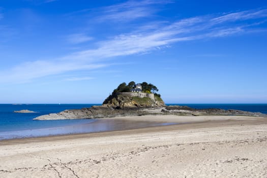 Landscape, seascape with beach and a house on top of a rock.