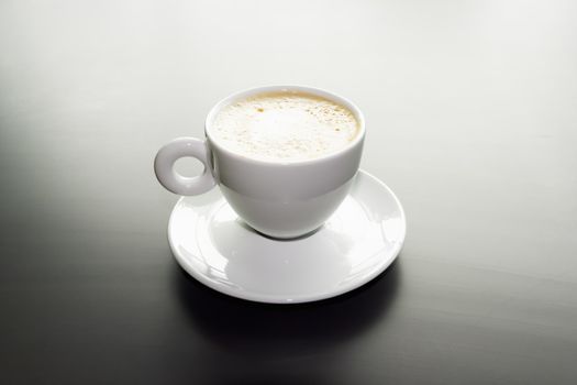 white cup of cappuccino on a black matte surface