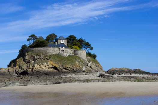 Landscape, seascape with beach and a house on top of a rock. 