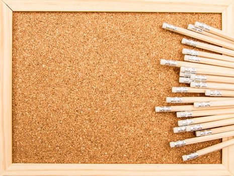 Bunch of wooden pencils over a cork board
