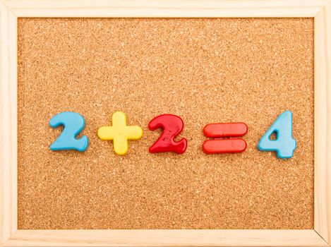 Simple mathematic addition on a wooden frame cork board
