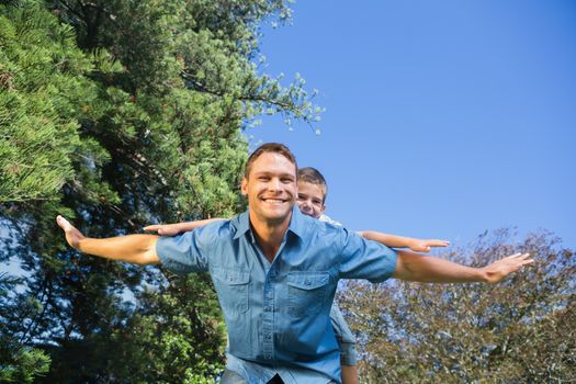 Happy child playing with his father outside in the park in summer