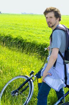Man cyclist relaxing against the background of green fields in spring on a sunny day