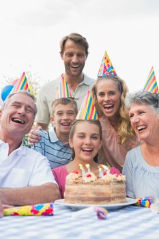 Happy extended family celebrating a birthday laughing at camera outside