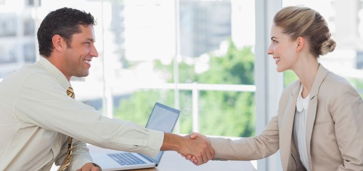 Blond businesswoman having an interview in office and shaking hands with interviewer