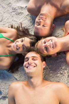 Overhead of cheerful friends lying together in a circle on the beach