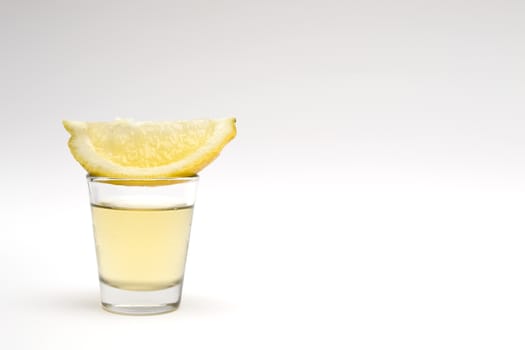 Tequila shot with lemon slice on a white background