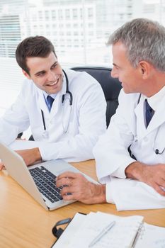 Doctors working together on laptop in bright office