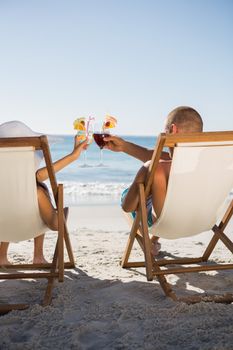 Happy couple clinking their glasses on the beach