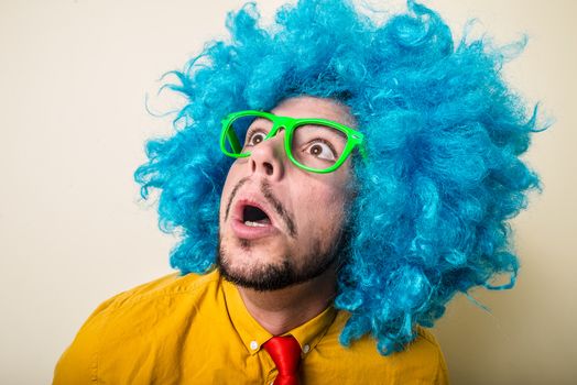 crazy funny young man with blue wig on white background