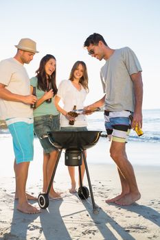 Happy young friends having barbecue together on the beach