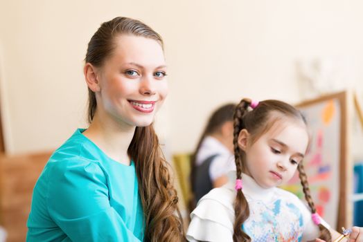 teacher talks to a schoolgirl, working at an art school