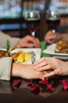Close up on couple holding hands during dinner in a romantic restaurant