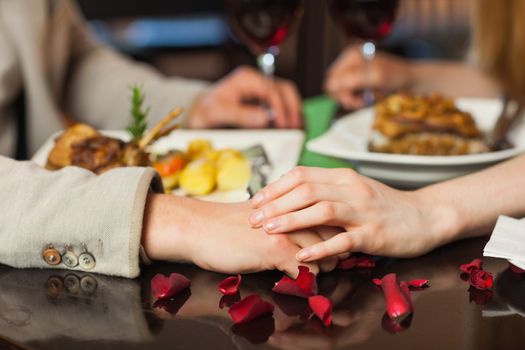 Close up on loving couple holding hands during romantic dinner