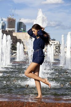 Young sexy woman in a city fountain
