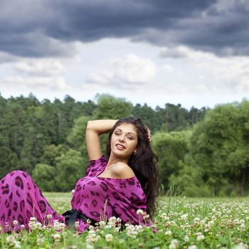 Portrait of young woman sitting on a green lawn